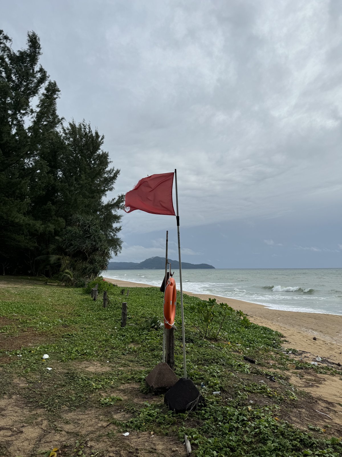 雨季的清晨海灘插著紅旗,幾乎沒人。這面旗就是叫你別下水的意思——再美再淺都別賭。