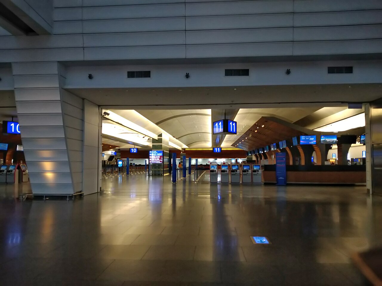 台灣桃園國際機場出境大廳深夜,空曠的自動報到機與櫃台走廊