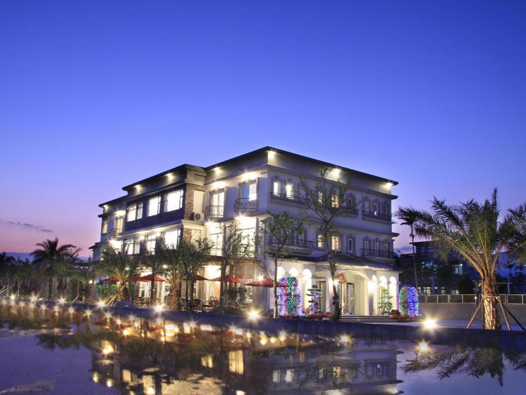 春水笈的白色歐式建築夜景，一樓拱窗透出暖光，前方水池映著燈影