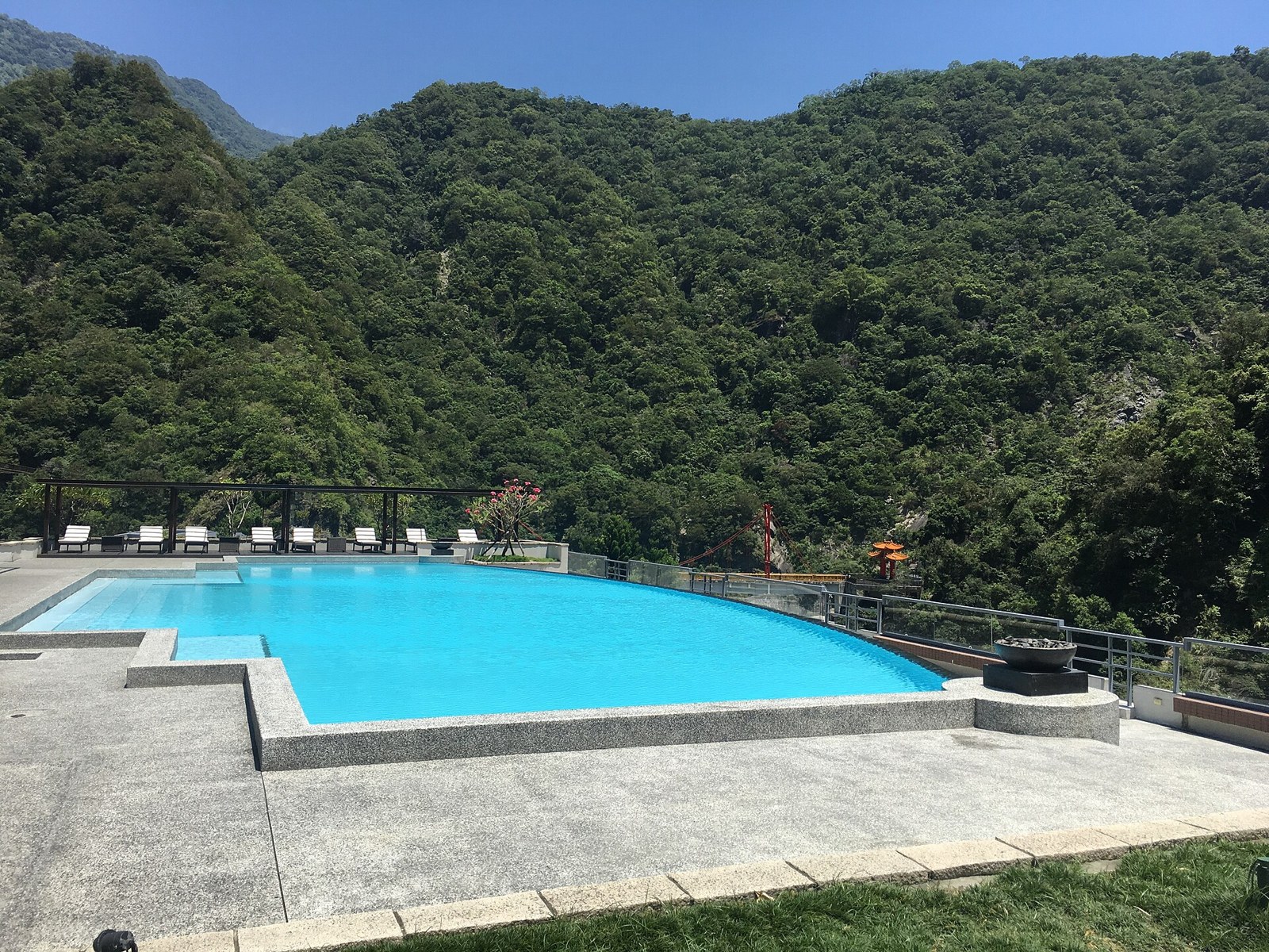太魯閣晶英酒店的戶外泳池，泳池水面平靜，池邊排著躺椅，背後是太魯閣的山壁與樹林。