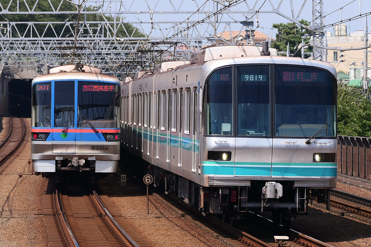 東京Metro南北線列車（右，綠色線條）與都營地下鐵三田線列車（左，藍色線條）在同一月台交會——兩間不同公司、卻能直通運轉，這也是新手最容易搞混「Metro」跟「都營」差別的地方