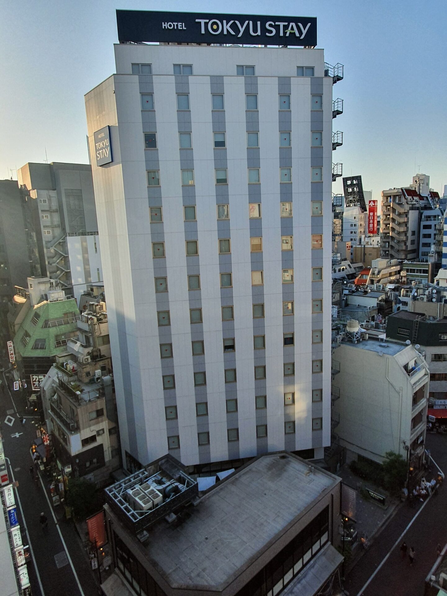 東急 STAY 新宿的外觀,白色建築頂端掛著 HOTEL TOKYU STAY 招牌,周圍是新宿三丁目的街區。